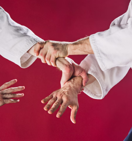 Manos de un maestro enseñando una sujeción a una alumna en una clase privada de artes marciales en Madrid