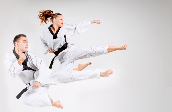 Dos adultos realizando una patada en salto durante una clase privada de artes marciales en Madrid