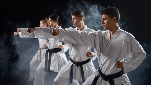 Grupo de adolescentes en pose de kárate en un entorno fotográfico con fondo profesional en una escuela de artes marciales en Madrid