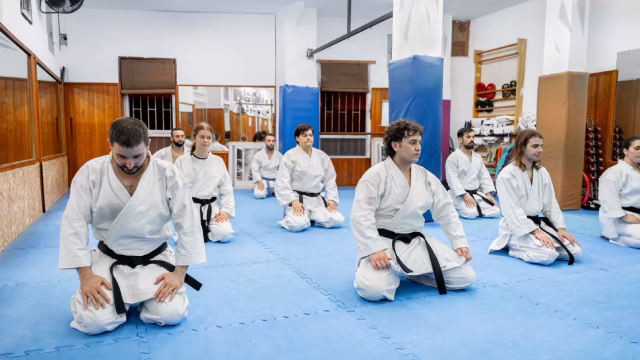 Group of teens and adults kneeling on a tatami during a karate class in Madrid