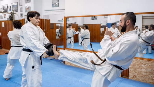 Maestro y alumno practicando taekwondo en una clase con adultos entrenando sobre tatami en una escuela y academia en Madrid