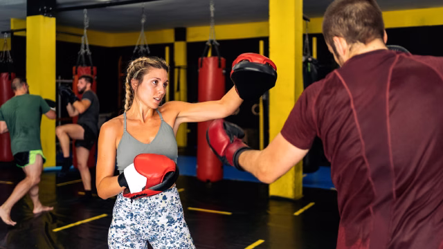 Grupo de adultos entrenando kickboxing en una clase de una escuela y academia en Madrid